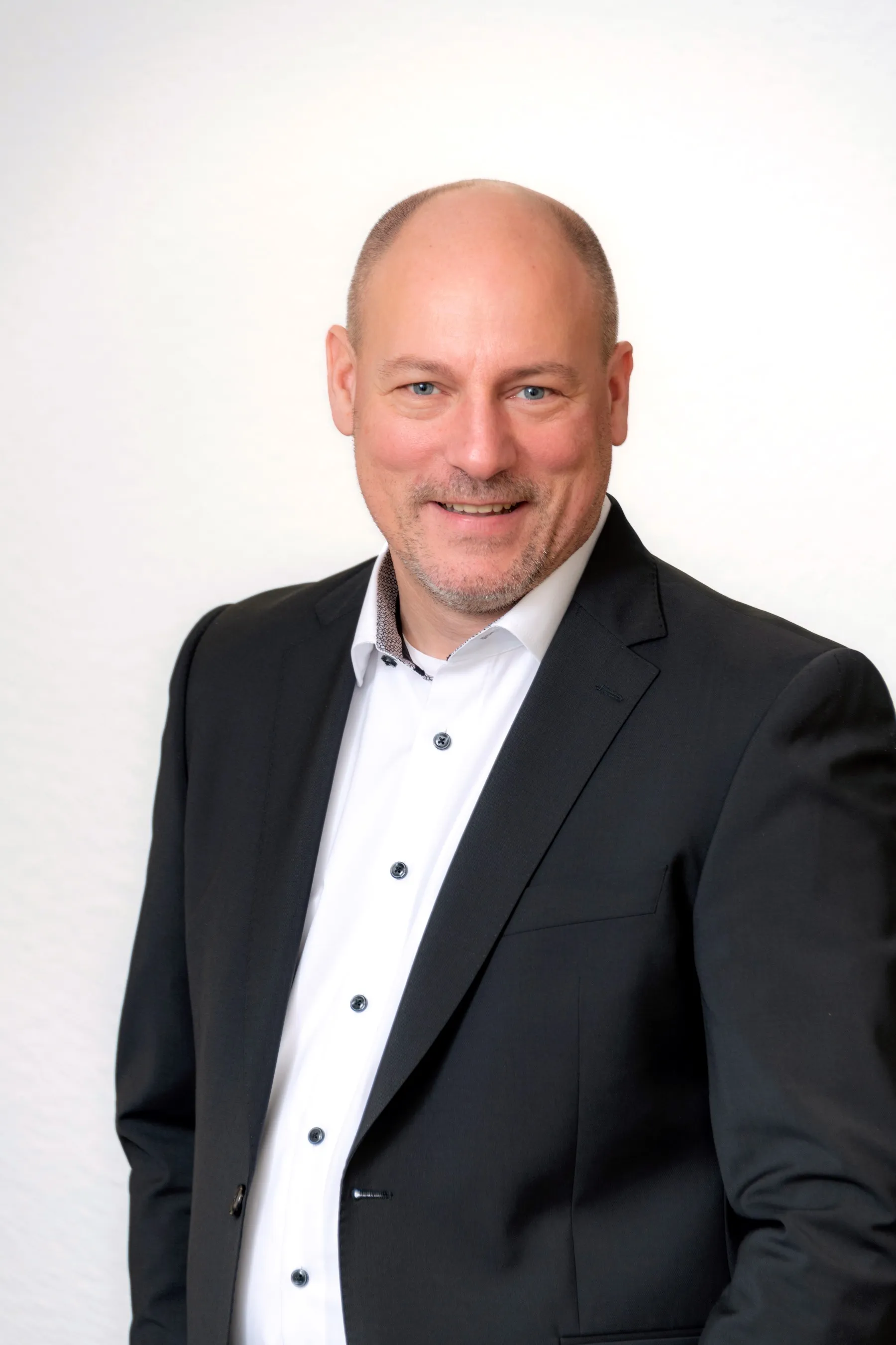 Porträtfoto eines Mitarbeiters der Steuerkanzlei im schwarzen Anzug und weißem Hemd.