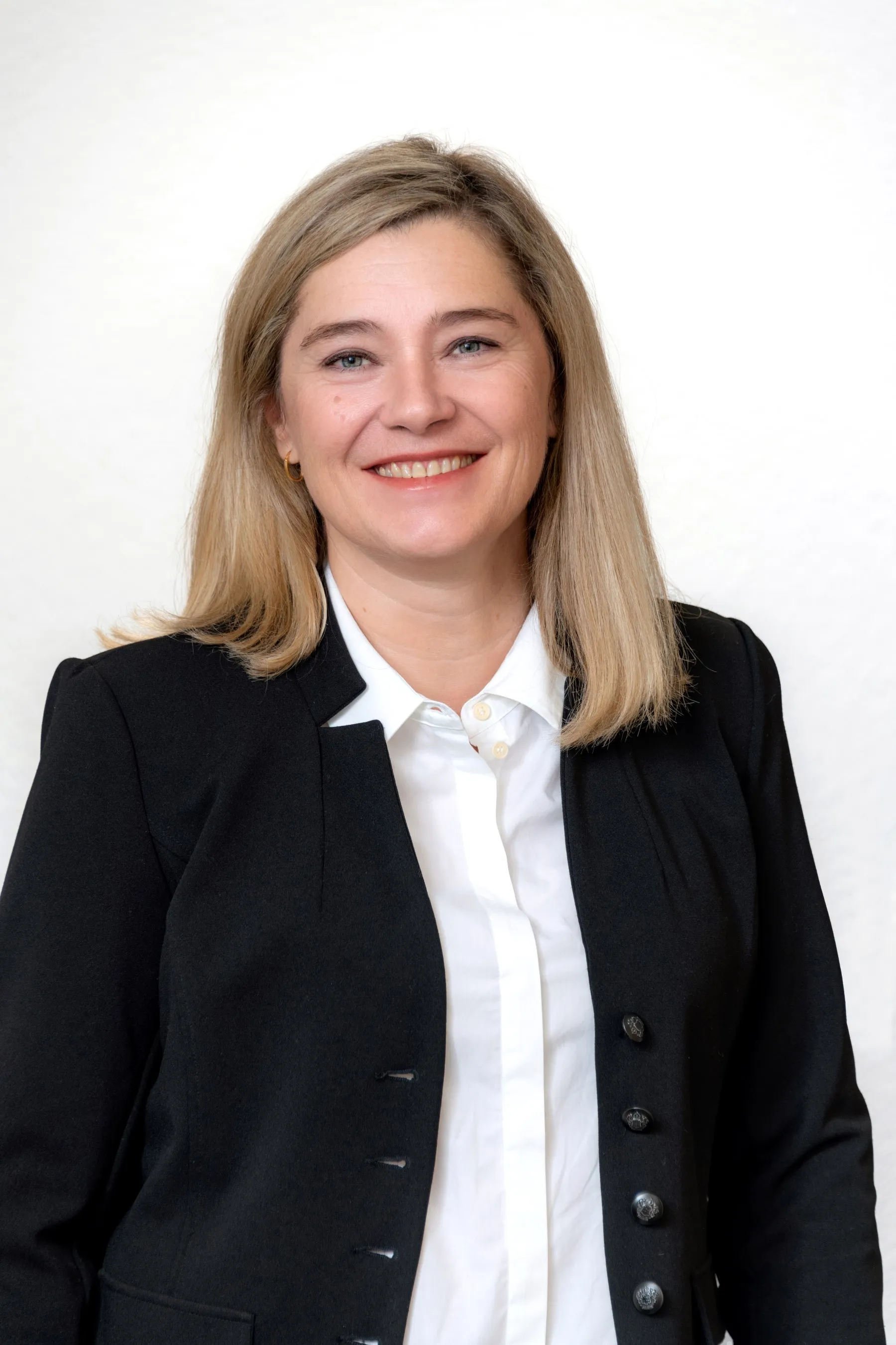 Porträtfoto einer Mitarbeiterin der Steuerkanzlei mit schulterlangen blonden Haaren, im schwarzen Blazer und weißer Bluse.